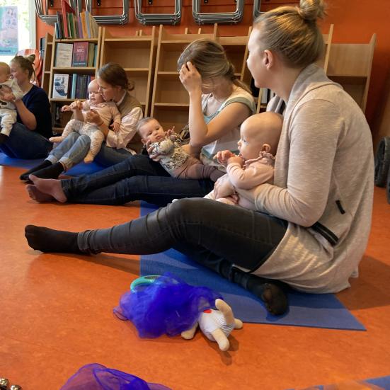 Mødre med babyer sidder på gulv og leger