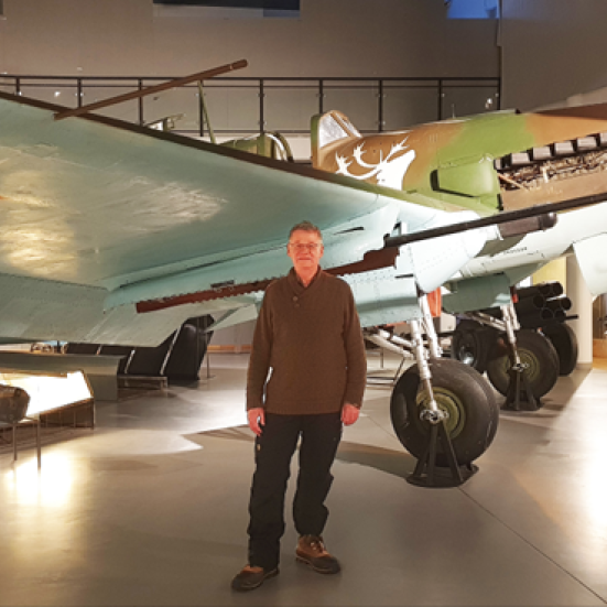 Foredragsholder Ivan Bæhr står ved siden af et russisk jagerfly fra 2. verdenskrig på et museum.