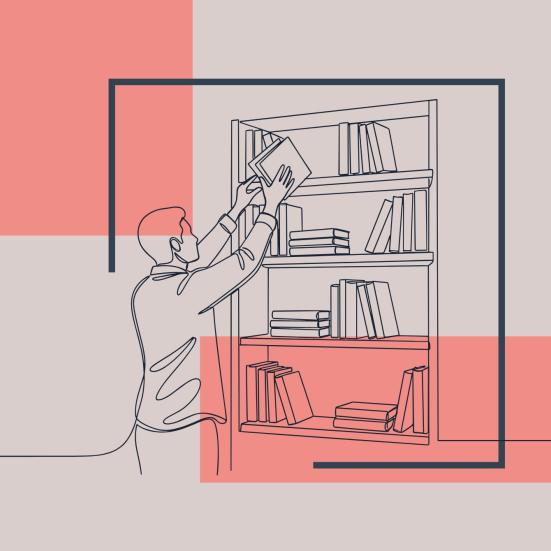 En fyr står ved en bogreol og trækker en bog ud fra øverste hylde.