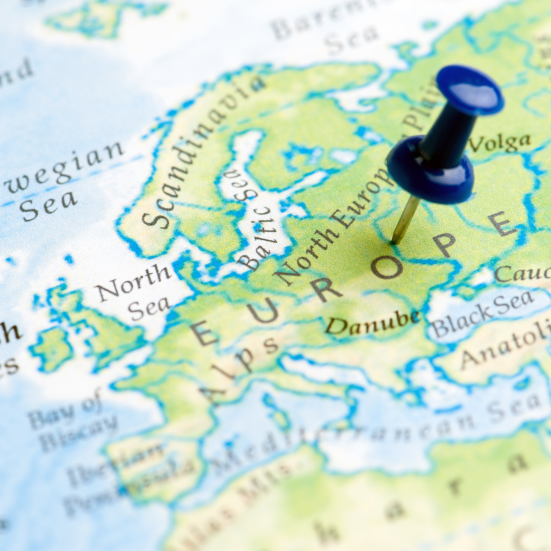 Nærbillede af Europakort med en blå knappenål markeret på kortet.