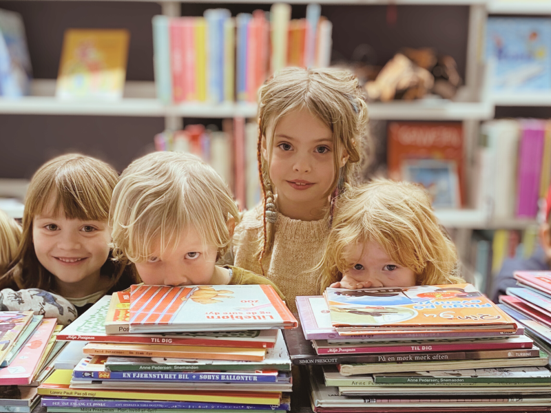 En gruppe børn ser på læsestof på biblioteket.