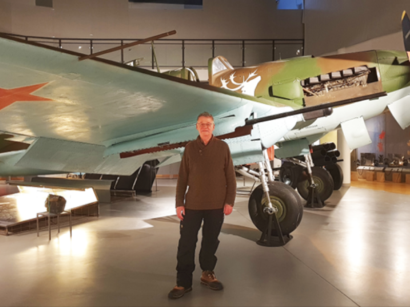 Foredragsholder Ivan Bæhr står ved siden af et russisk jagerfly fra 2. verdenskrig på et museum.