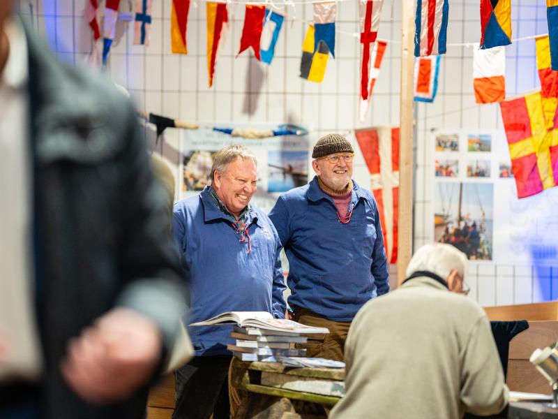 Et par hyggelig ældre gutter i sømandsbusseronner står og griner under et arrangement i Slagteribygningen.