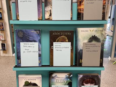 Bøger stablet op på hylder, udstillet og anbefalet af skolepraktikant. 