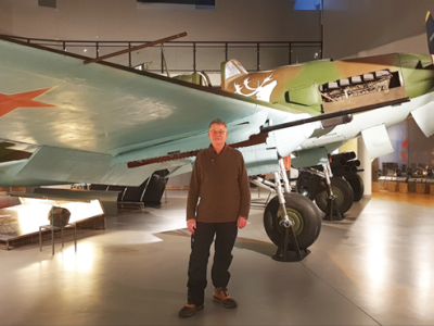 Foredragsholder Ivan Bæhr står ved siden af et russisk jagerfly fra 2. verdenskrig på et museum.