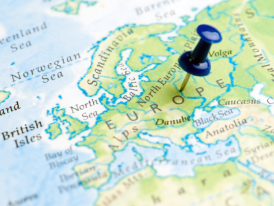 Nærbillede af Europakort med en blå knappenål markeret på kortet.
